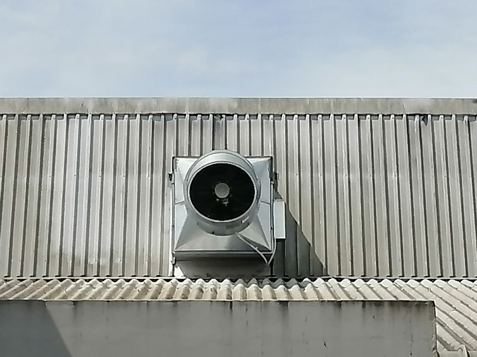 Roof-mounted axial extractor with weather cowl — factory wall