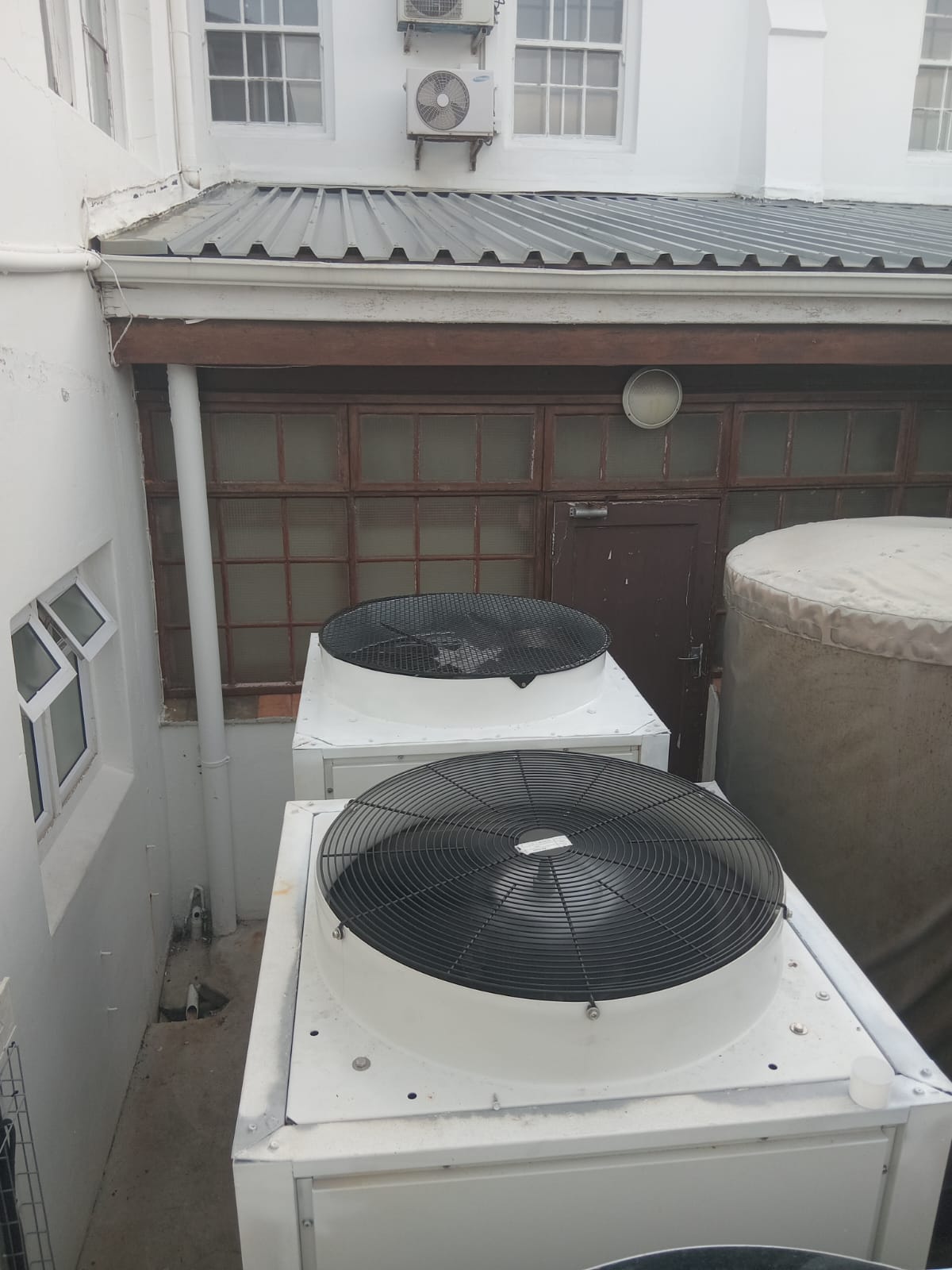 Site-fitted condenser protection cages — outdoor courtyard installation